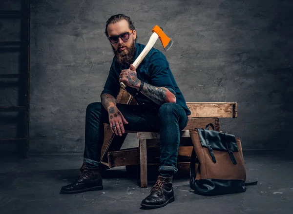 Hombre tatuado con gafas de sol sosteniendo un hacha . — Foto de Stock