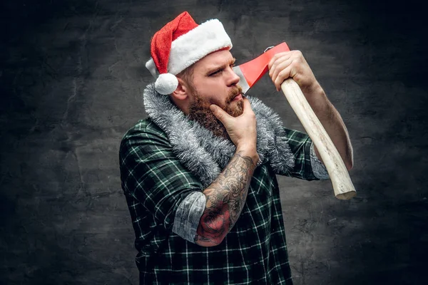 Mann mit Weihnachtsmannhut hält Axt in der Hand — Stockfoto