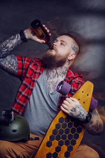 Tattooed skateboarder drinking beer — Stock Photo, Image