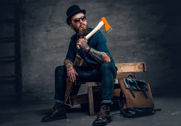 Hombre con brazos tatuados sosteniendo un hacha — Foto de Stock