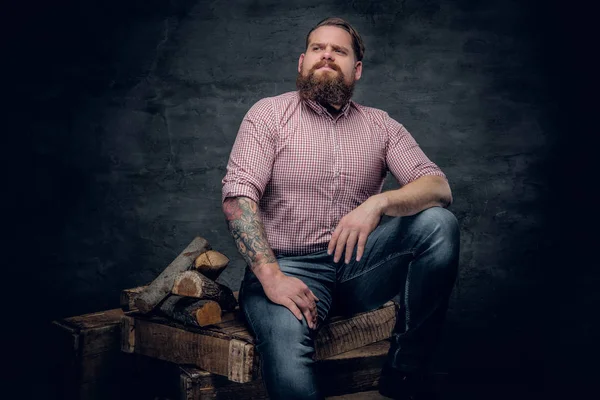 Man sitting on a box near firewoods — Stock Photo, Image