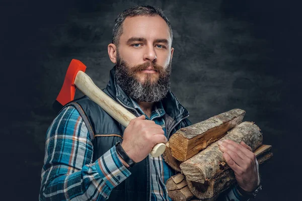 Hombre barbudo sosteniendo un hacha y leña —  Fotos de Stock