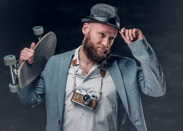 Homem elegante segurando skate e câmera — Fotografia de Stock