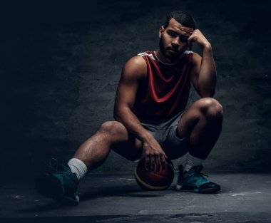 Sepet topu üzerinde oturan basketbolcu