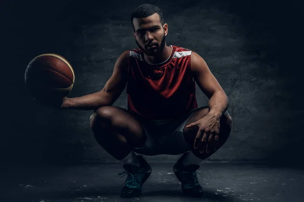 Jogador de basquete agachamento e segurando bola — Fotografia de Stock