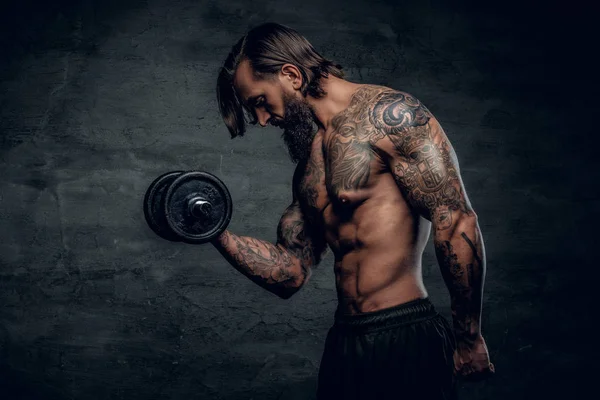 Man with tattooed body holding dumbbell — Stock Photo, Image