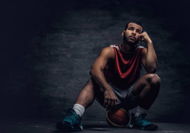 Sepet topu üzerinde oturan basketbolcu