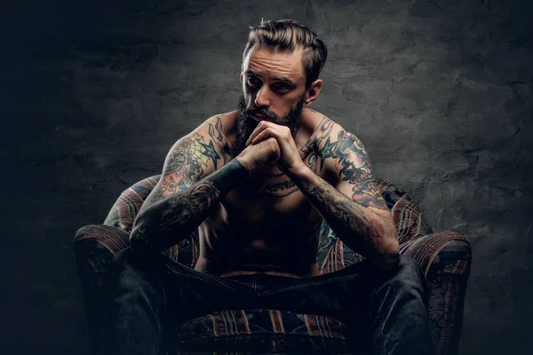 Félmeztelen, tetovált ember ül egy széken — Stock Fotó