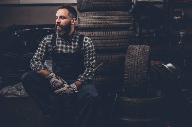 Mekanik bir eski lastiklerle oturmuş sakallı