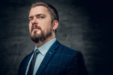 Sakallı adam bir takım elbise ve kravat giyiyor