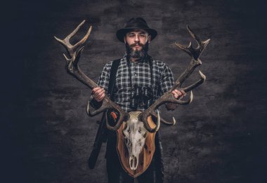 Bir geyik kafatası tutan avcı adam