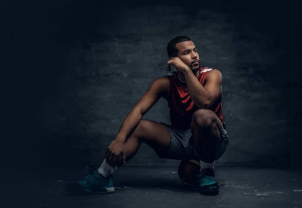 Jugador de baloncesto sentado en la pelota de baloncesto — Foto de Stock