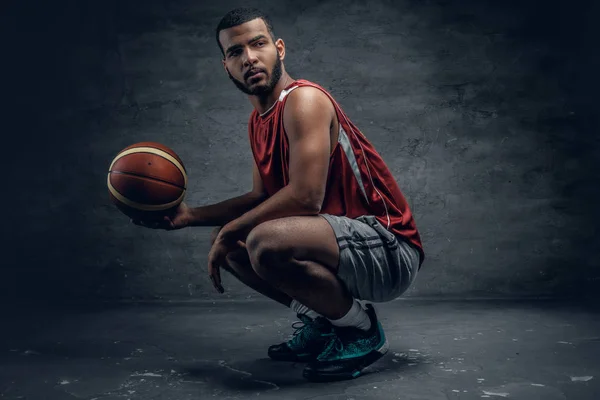 Jogador de basquete agachamento e segurando bola — Fotografia de Stock