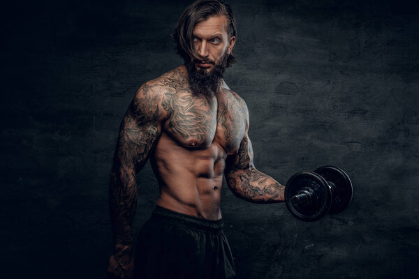 Man with tattooed body holding dumbbell