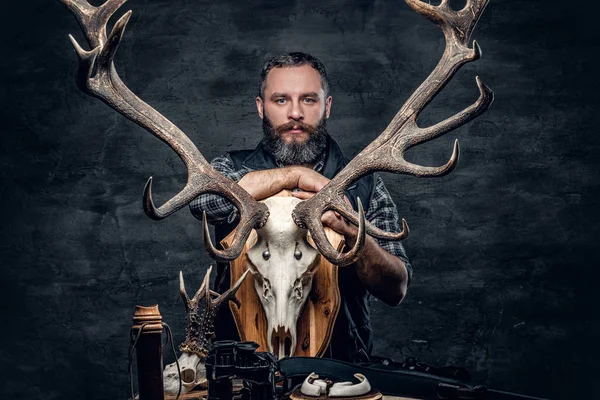 Bir geyik kafatası tutan avcı adam