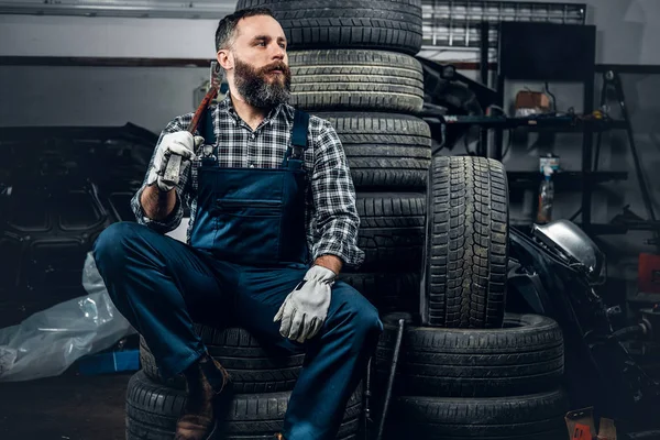 Mecánico se sienta en un neumático viejo —  Fotos de Stock
