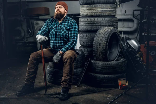 Механик сидит на старых шинах — стоковое фото