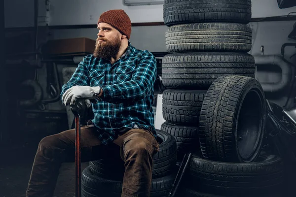Mecánico se sienta en un neumático viejo —  Fotos de Stock