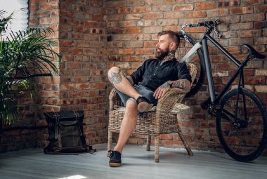 Sakallı adam bir sandalyede oturur