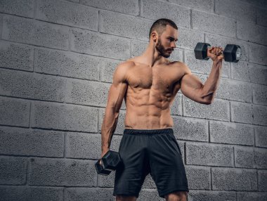 Gömleksiz erkek dumbbells ile egzersiz yapıyor
