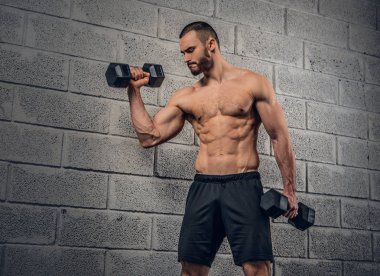 Gömleksiz erkek dumbbells ile egzersiz yapıyor