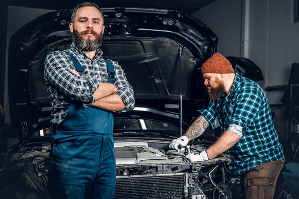 Two bearded men repairing a car