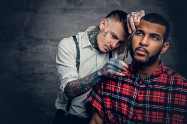 Tattooed barber cuts the beard clipart