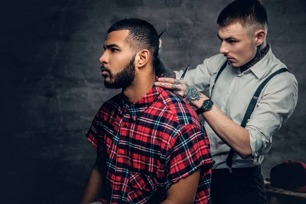 Tattooed barber cuts the beard — Stock Photo, Image