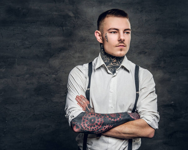 Человек с татуировками и скрещенными руками
