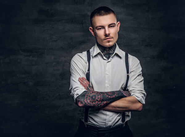 Человек с татуировками и скрещенными руками
