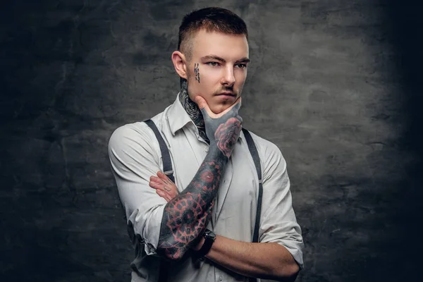 Tattooed man wearing shirt and suspenders