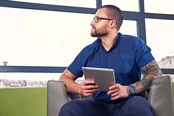 Bearded male in eyeglasses using a tablet — Stock Photo, Image