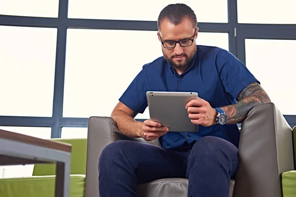 Bearded male in eyeglasses using a tablet — Stock Photo, Image