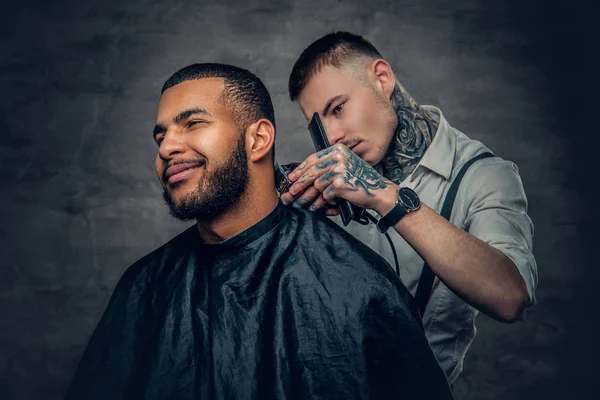 Татуированный парикмахер стрижет бороду — стоковое фото
