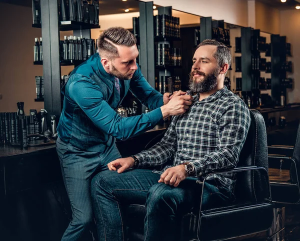 Barbeiro corta a barba de um homem — Fotografia de Stock