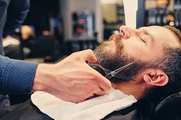 Barber cuts man's beard. — Stock Photo, Image