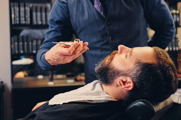 Barber cuts man's beard. — Stock Photo, Image
