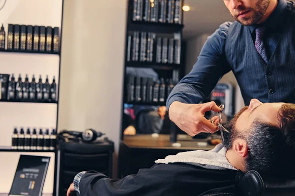 Peluquero corta la barba del hombre . — Foto de Stock