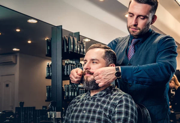 Стильный парикмахер, ухаживающий за бородой мужчины — стоковое фото