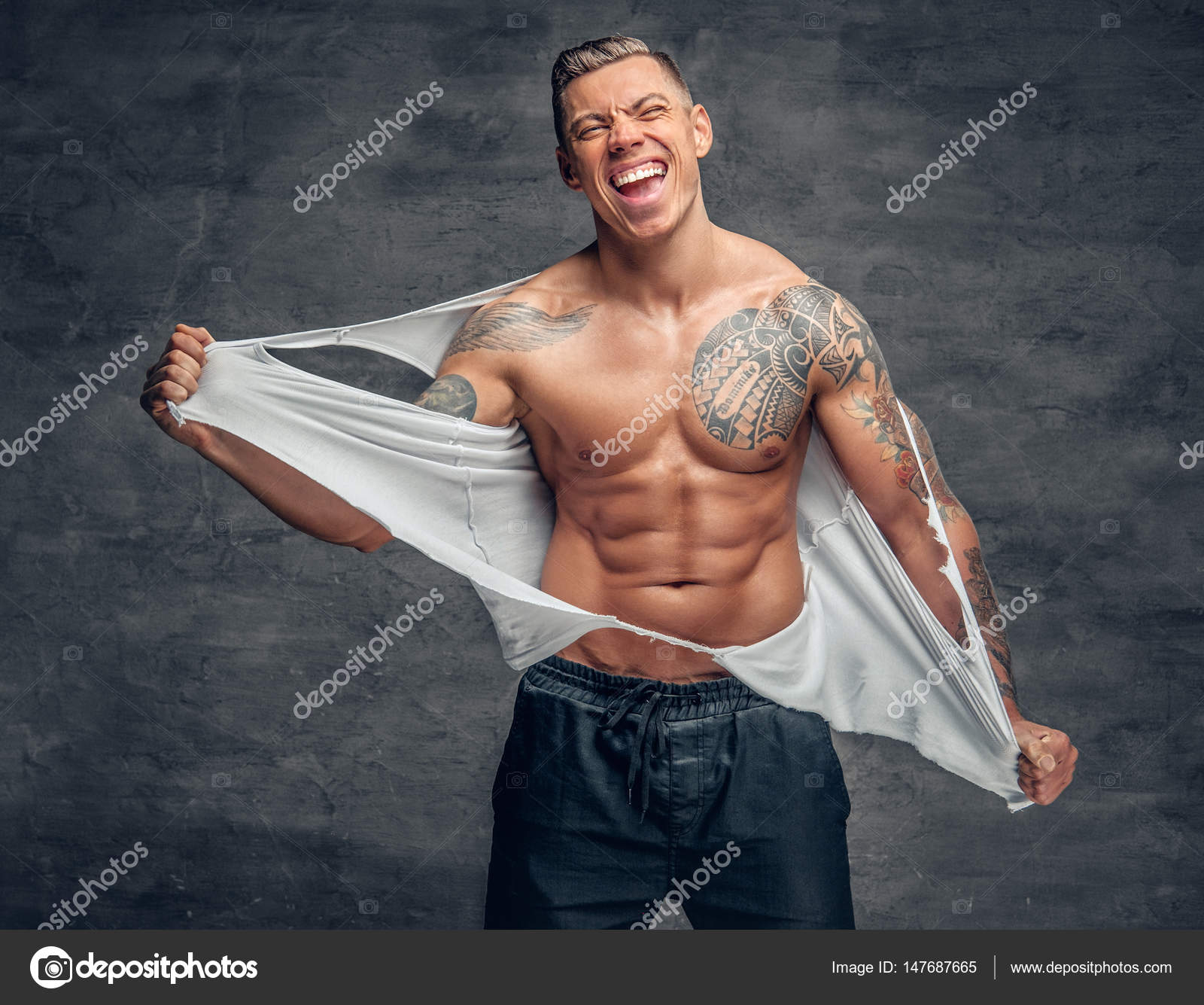 Athletic male with a tattoo ripping t shirt on his chest. Stock Photo by  ©fxquadro 147687665