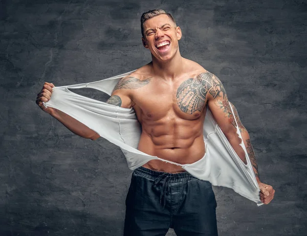 Atletische man met een tatoeage rippen t shirt op zijn borst. — Stockfoto