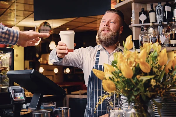 Bearded barista selling coffee to a consumer — Stock Photo, Image
