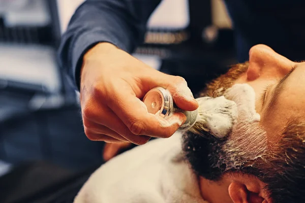 Barbeiro barbear um homem com uma navalha afiada — Fotografia de Stock