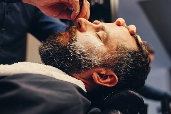 Peluquero afeitando a un hombre con una navaja afilada — Foto de Stock