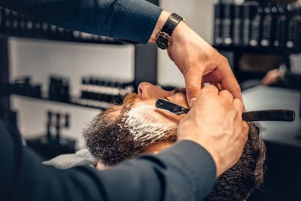 Barber shaving a man with a sharp razor — Stock Photo, Image