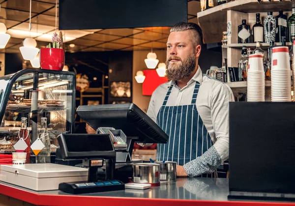 En positiv skjeggete mann ved disken – stockfoto