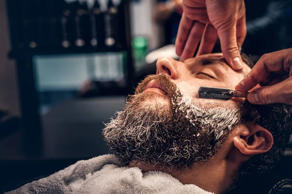 Holič, holení muže s ostrým jako břitva — Stock fotografie