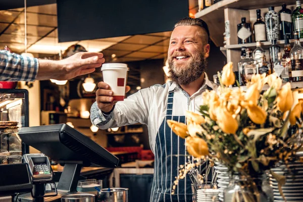 Barista barbudo vendendo café a um consumidor — Fotografia de Stock