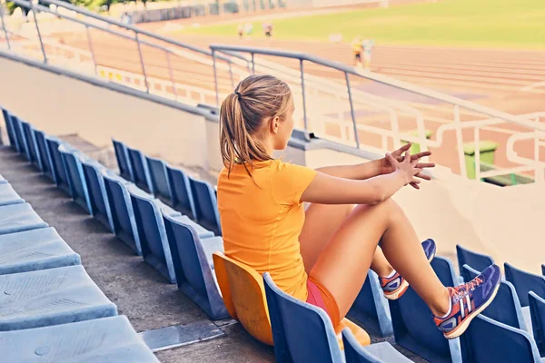 Sporty femmina si siede sul sedile dello stadio — Foto Stock