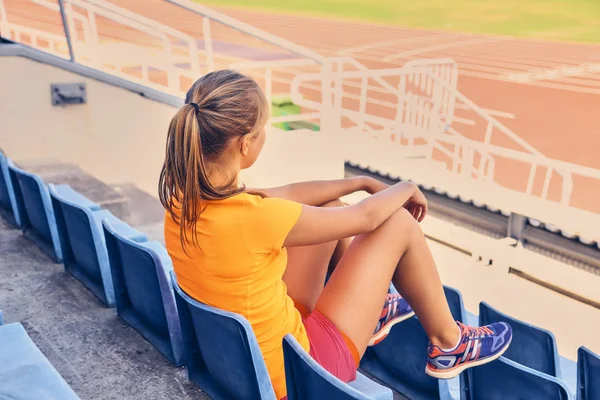 スポーティな女性がスタジアムの座席に座っています。 — ストック写真